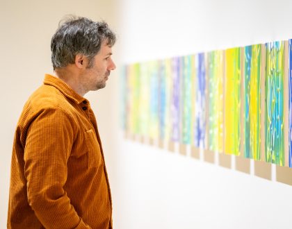 A person looking at a series of monoprint artwork in a exhibition space at the Varley Art Gallery of Markham.