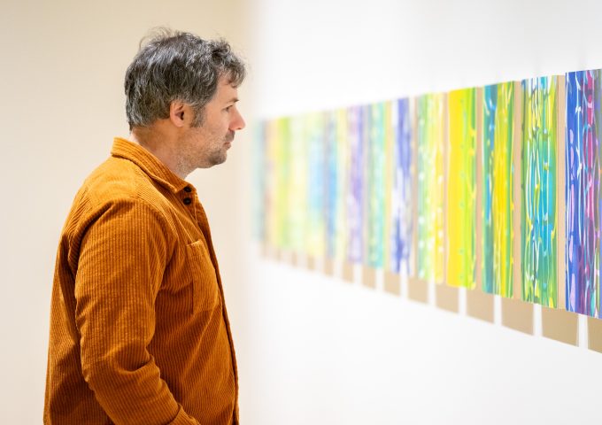 A person looking at a series of monoprint artwork in a exhibition space at the Varley Art Gallery of Markham.