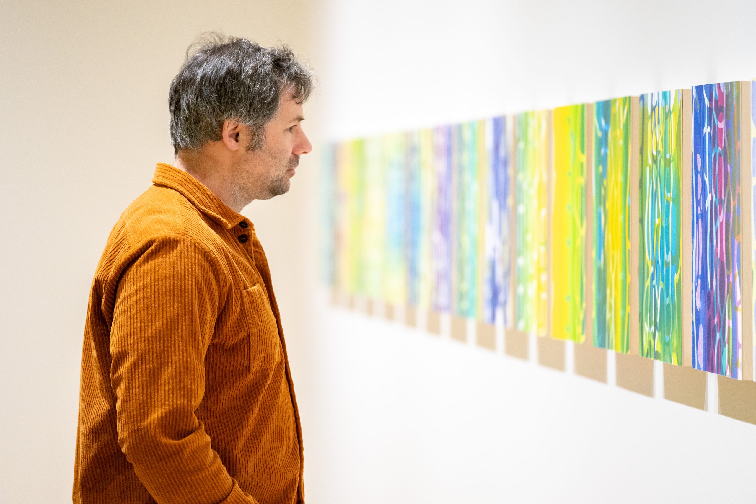 A person looking at a series of monoprint artwork in a exhibition space at the Varley Art Gallery of Markham.